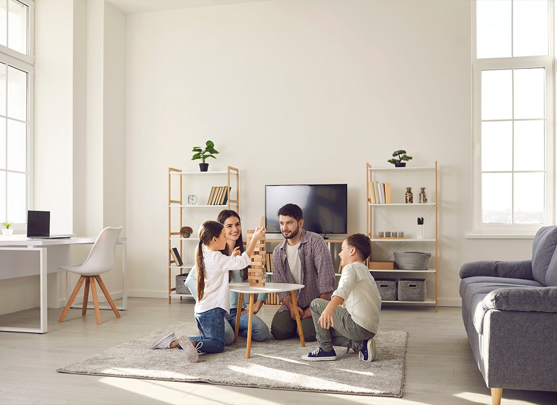 Personal Insurance - A Happy Family Spending Time Together and Playing Jenga on Their LIving Room Floor