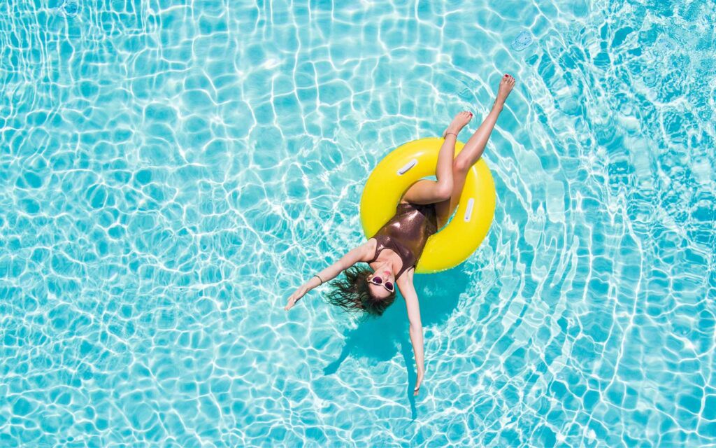 Lagoon Insurance - Areial View of Woman Relaxing in a Black Bathing Suite While Sitting in a Yellow Tub in a Pool on a Nice Sunny Day