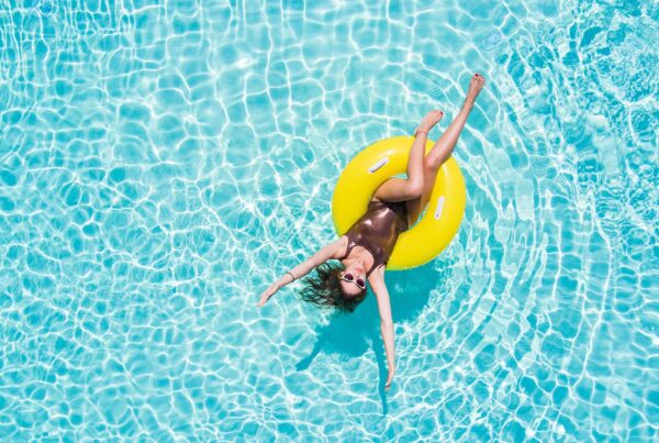Lagoon Insurance - Areial View of Woman Relaxing in a Black Bathing Suite While Sitting in a Yellow Tub in a Pool on a Nice Sunny Day